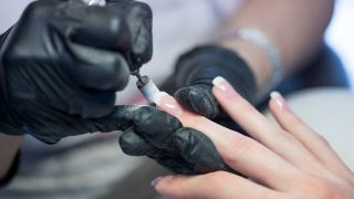 Eine Kosmetikerin feilt in einem Nagelstudio die Gelnaegel einer Kundin in Form (Quelle: dpa/Christin Klose)