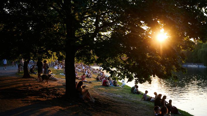Viele Menschen sitzen bei sehr warmem Wetter in der Abendsonne am Ufer des Landwehrkanales. (Quelle: dpa/Annette Riedl)