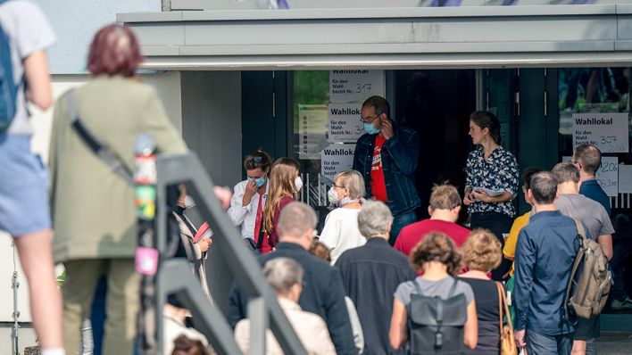 Zahlreiche Menschen stehen in einer langen Schlange vor den Wahllokalen im Tiergarten Gymnasium in der Altonaer Straße (Bild: dpa/Monika Skolimowska)
