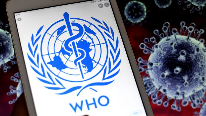 Symbolbild: Das Logo der WHO vor Corona-Virus-Illustrationen. (Quelle: dpa/A. Das)