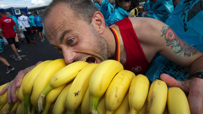 Ein Marathon-Läufer beißt beim Berlin-Marathon 2012 in einen Stapel Bananen. Bild: imago-images/Camera 4