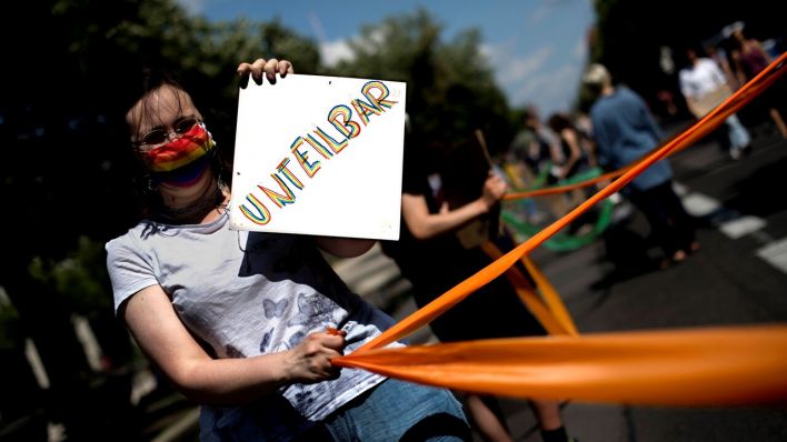 Frau hält Plakat mit der Aufschrift "Unteilbar" (Quelle: imago/Stefan Boness)