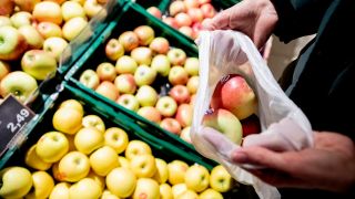 Eine Frau füllt in einem Supermarkt in Berlin-Wilmersdorf ein Mehrwegnetz mit Äpfeln. (Quelle: dpa/Christoph Soeder)