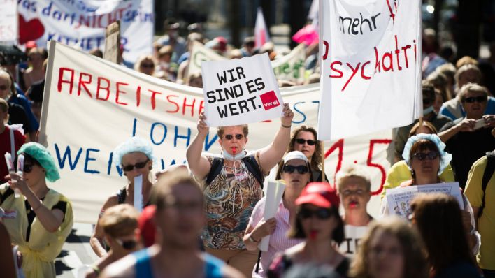 Eine Demoteilnehmerin hält ein Schild mit der Aufschrift "WIR SIND ES WERT." (Quelle: dpa/Gregor Fischer)