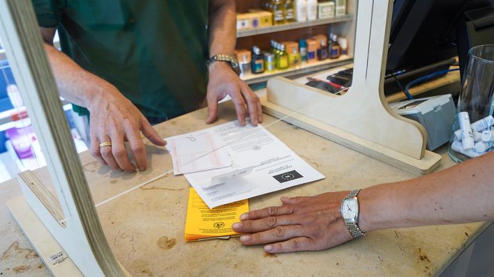 Eine Kundin übergibt ihren Impfpass und ein Covid-19 Impfzertifikat in einer Pankower Apotheke, um sich einen digitalen Impfnachweis ausstellen zu lassen (Bild: dpa/Jörg Carstensen)