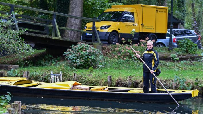 Andrea Bunar, Zustellerin der Deutschen Post, ist in ihrem gelben Postkahn unterwegs, während am Ufer ihr neues Elektrofahrzeug steht. (Quelle: dpa/Patrick Pleul)