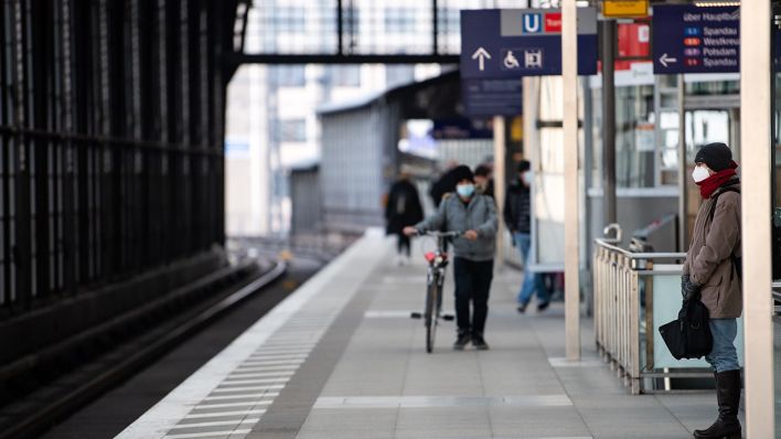 Fahrgäste mit Mund-Nasen-Bedeckungen warten am Bahnhof Friedrichstraße in Mitte auf eine S-Bahn. (Quelle: dpa/Bernd von Jutrczenka)