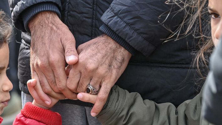 Symbolbild: Ein Vater hält die Hände seiner beiden Töchter in einer Einrichtung für Asylbewerber. (Quelle: dpa/Patrick Pleul)