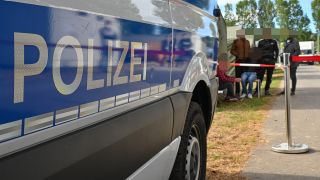 Ein Fahrzeug der Polizei steht vor Migranten in der Zentralen Erstaufnahmeeinrichtung für Asylbewerber (ZABH) des Landes Brandenburg. (Quelle: dpa/P. Pleul)