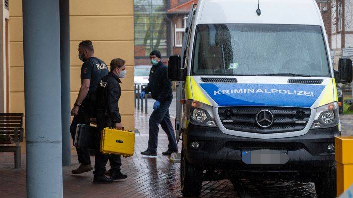Archivbild: Ein Mitarbeiter der Kriminalpolizei geht mit zwei kleinen Handkoffern auf dem Gelände einer Potsdamer Klinik zu einem Polizeiauto. In der Klinik sind vier Leichen gefunden worden. (Quelle: dpa/C. Gateau)