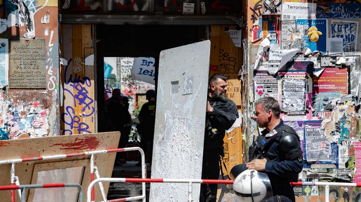 Ein Polizeibeamter trägt ein übergroßes Schutzschild aus dem Haus Nr. 94 in der Rigaer Straße (Bild: dpa/Paul Zinken)
