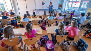 Eine Lehrerin steht vor den Schülerinnen und Schülern einer dritten Klasse. Quelle: dpa/Jens Büttner