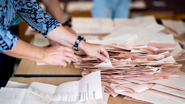 Eine Wahlhelferin sortiert in einer Grundschule, in der ein Wahllokal für die Kommunalwahl untergebracht ist, die Stimmzettel für die Auszählung. (Quelle: dpa/Hauke-Christian Dittrich)