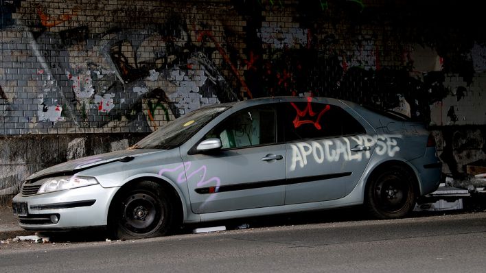 Archivbild: "Apocalypse" steht auf einem ausrangierten, zerstörten und bemalten Autowrack am Weigandufer, Berlin. (Quelle: dpa/P. Zinken)