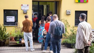 Am Wahlsonntag warten Menschen vor einem Wahllokal im Berliner Bezirk Neukölln. Quelle: imago images