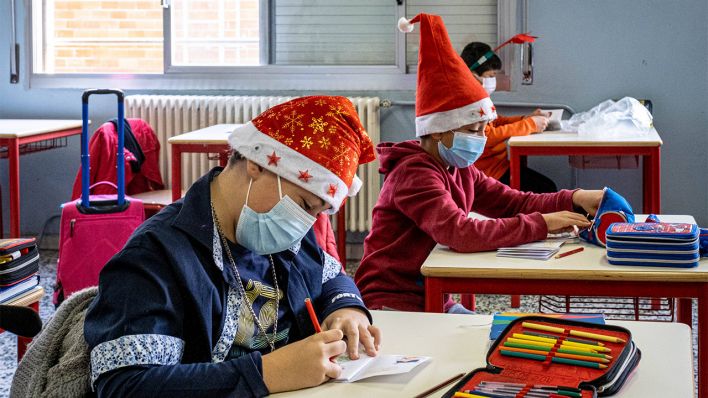 Symbolbild: Kinder der vierten Klasse sitzen mit Weihnachtsmützen in einer Schulklasse (Bild: imago images/Marco Passaro)