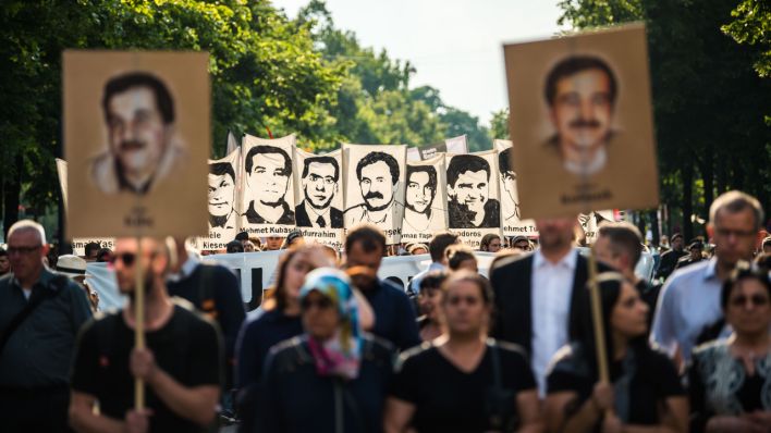 Demonstranten halten bei einer Kundgebung Schilder mit Porträt Abbildungen der NSU-Opfer. (Quelle: dpa/Lino Mirgeler)