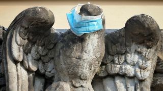 Dem steinernen Adler über dem Eingang einer Haustür in der Potsdamer Innenstadt wurde eine OP-Maske um den Schnabel gebunden.