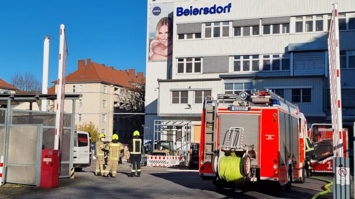 Feuerwehrleute und Einsatzfahrzeuge stehen vor einem Produktionsbetrieb von Beiersdorf. Dort waren am Vormittag Chemikalien ausgetreten. (Quelle: TNN/Dpa/Cevin Dettlaff)