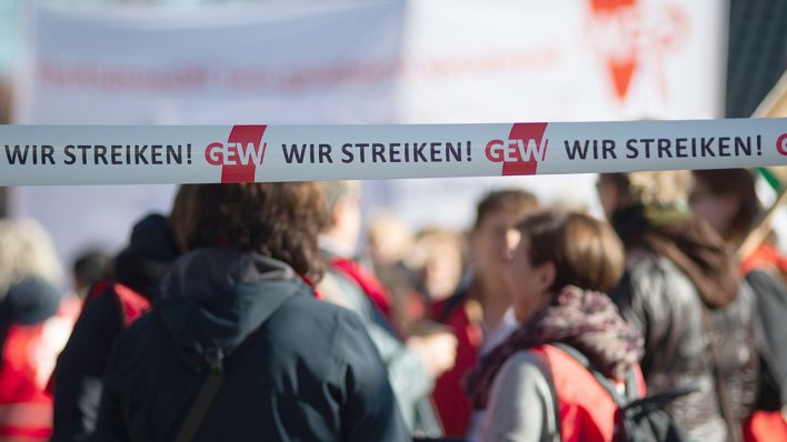 Archivbild: "Wir Streiken" und "GEW" steht auf zwei Flatterbändern hinter denen Teilnehmer eines Warnstreiks stehen (Bild: dpa/Klaus Dietmar Gabbert)