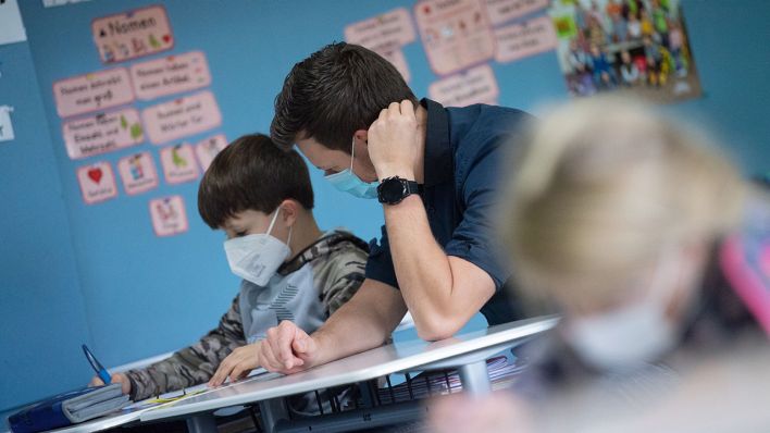 Symbolbild: Ein Schüler sitzt während des Unterrichts mit Maske neben dem Klassenlehrer. (Quelle: dpa/M. Murat)
