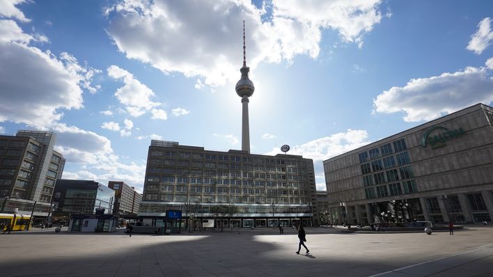 Symbolbild: Der Fernsehturm wirft einen riesigen Schatten auf den Alexanderplatz, während eine einzige Person über den großen Platz geht. (Quelle: dpa/J. Carstensen)