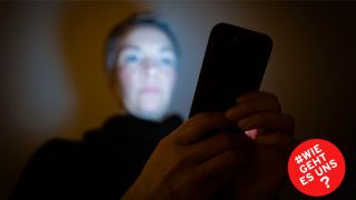 Symbolbild: Eine Frau schaut in einem dunklen Raum auf ihr Smartphone. (Quelle: dpa/Thomas Trutschel)