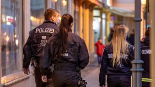 Mitarbeiterinnen des Ordnungsamts und ein Polizeibeamter laufen auf der Berliner Straße. (Quelle: dpa/Frank Hammerschmidt)