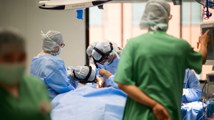 Archivbild: Ein Team aus Ärzten und OP-Helfern steht während einer Operation um einen Patienten. (Quelle: dpa/J. Güttler)