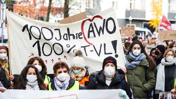„100 Jahre AWO - 100% T-VL!" steht auf dem Transparent, das Demonstrantinnen und Demonstranten in Wedding halten (Bild: dpa/Annette Riedl)