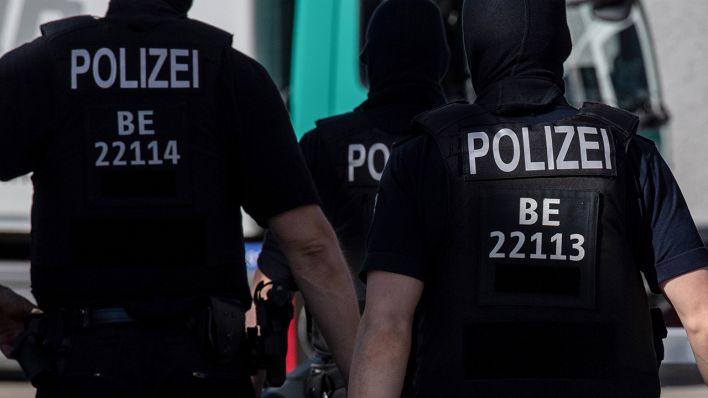 Polizisten gehen in Berlin vor einem Gebäude über die Straße. (Quelle: dpa/Paul Zinken)