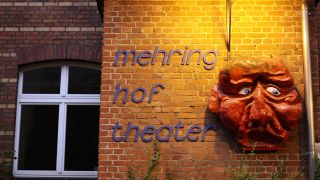 Schriftzug und Maske am Mehringhof-Theater in Berlin (Quelle: imago images/Gerhard Leber)