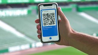 Ein digitaler Impfpass auf einem Smartphone in einem Fußball-Stadio(Bild: imago images/Foto2press)