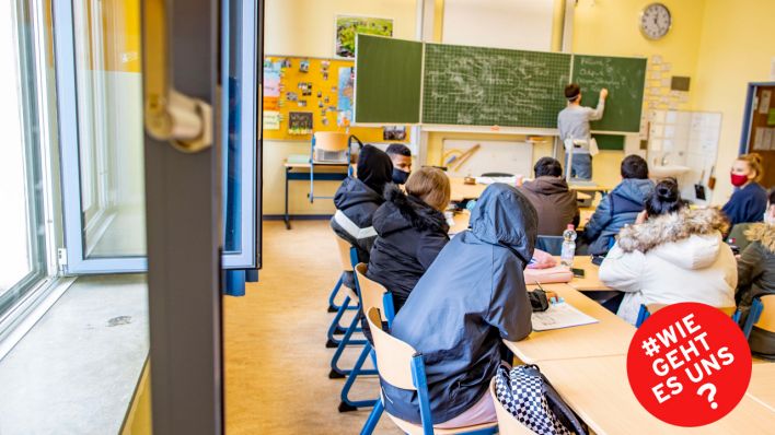 Schüler:innen sitzen in ihren dicken Winterjacken bei offenem Fenster in einem Klassenraum (Quelle: imago images/Christoph Reichwein)