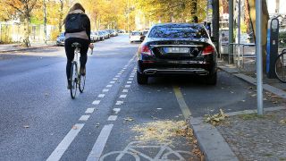 Symbolbild: Eine Radfahrerin fährt in Berlin Mitte auf der Straße, weil ein PKW auf dem Radweg parkt. (Quelle: dpa/A. Gora)