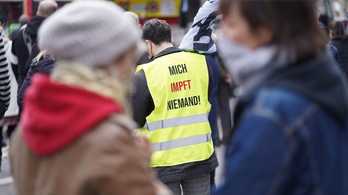 Ein Mann mit einer Weste mit der Aufschrift "Mich impft niemand" ist am 28.03.2021 auf einer Demonstration gegen Corona-Maßnahmen auf dem Rosa-Luxemburg-Platz zu sehen. (Quelle: dpa/Jörg Carstensen)