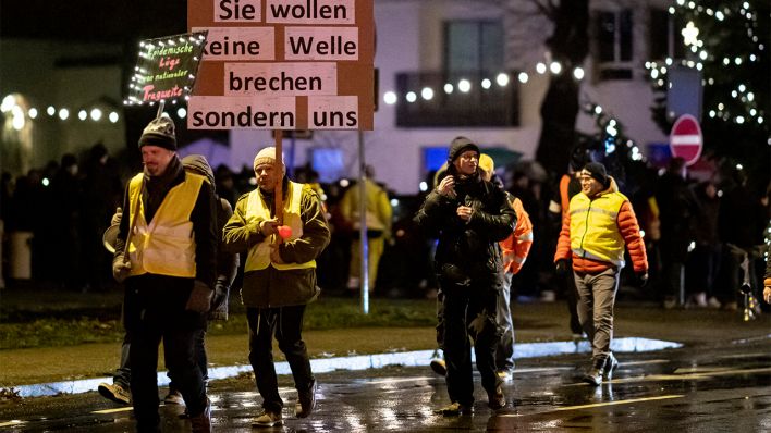Gegner der Corona-Maßnahmen laufen am 13.12.2021 mit einem Schild "Sie wollen keine Welle brechen sondern uns" auf einer Demo nahe dem Kirchplatz in Königs Wusterhausen. (Quelle: dpa/Fabian Sommer)