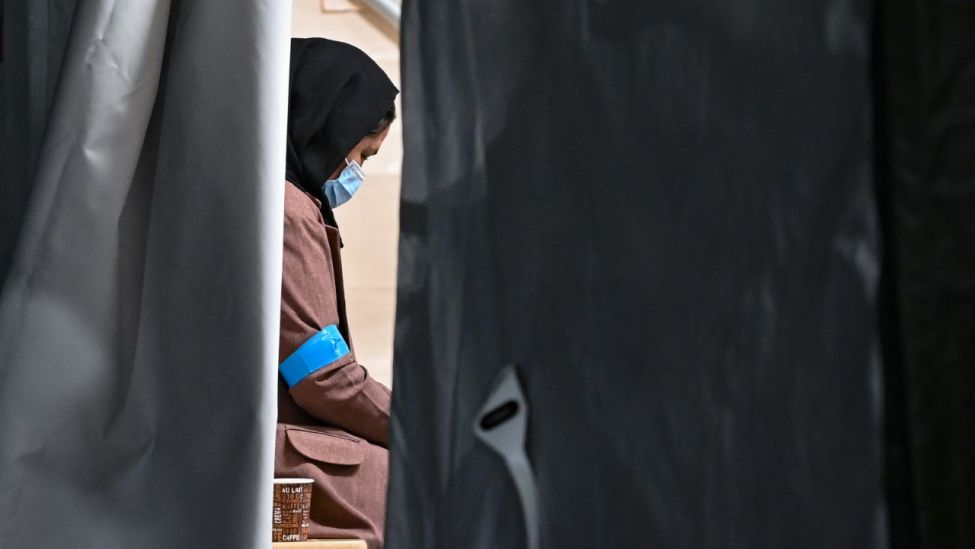 Eine Frau, die zusammen mit weiteren Ortskräften aus Afghanistan am 20.08.21 auf dem Gelände der DRK-Flüchtlingshilfe in der Erstaufnahmeeinrichtung in Brandenburg angekommen ist, sitzt in einem Zelt (Quelle: dpa / Patrick Pleul).