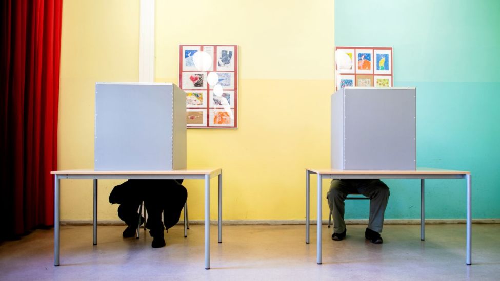 Wähler sitzen am 26.09.21 im Berliner Stadtteil Prenzlauer Berg in einem Wahllokal, das in einer Grundschule untergebracht ist, in den Wahlkabinen, um ihre Stimme für die Bundestagswahl und das Berliner Abgeordnetenhaus abzugeben (Quelle: dpa / Hauke-Christian Dittrich).