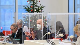 Symbolbild: Dietmar Woidke (M, SPD), Ministerpräsident von Brandenburg, sitzt während der Sondersitzung des Brandenburger Landtages vor der Kulisse eines geschmückten Weihnachtsbaumes. (Quelle: dpa/S. Stache)