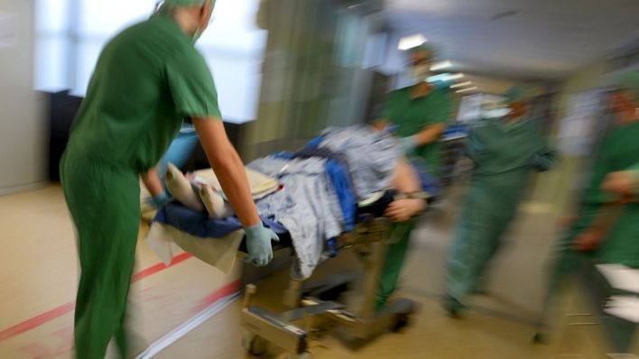 Symbolbild: Ein Mediziner-Team fährt in einer Klinik einen Patienten im Bett durch den Klinikflur. (Quelle: dpa/F. Kästle)