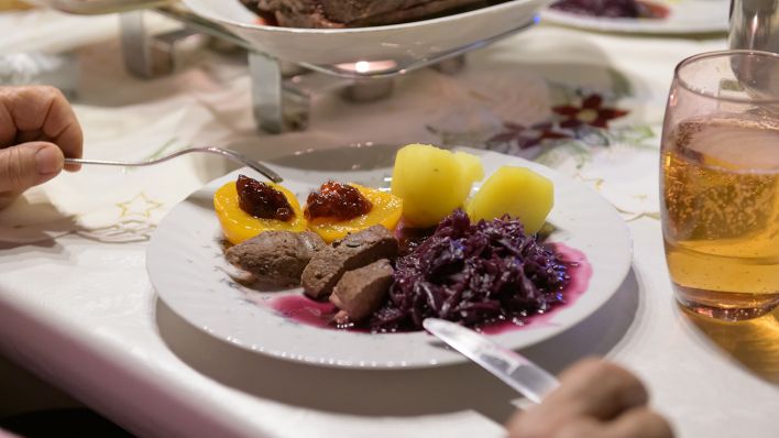 Damhirsch-Rücken mit Kartoffeln und Rotkohl sowie Preiselbeergelee auf Aprikosen liegen verzehrfertig auf einem Teller an Heiligabend. (Quelle: dpa/Jonas Walzberg)