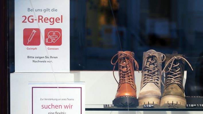 Ein Schild mit der Aufschrift „Bei uns gilt die 2G-Regel Geimpft Genesen“ hängt im Schaufenster eines Schuhgeschäftes in der Brandenburger Straße. (Quelle: dpa/Sören Stache)