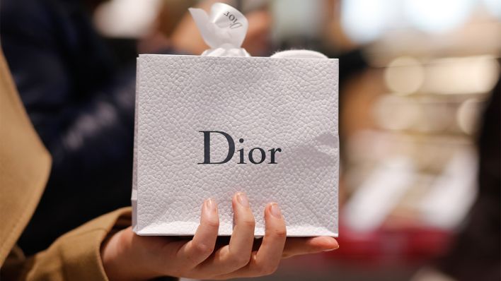 Eine Person hält eine Dior Tüte in der Hand (Bild: dpa/Gerald Matzke)