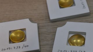 Drei Münzen aus dem Kelten-Schatz in Brandenburg liegen bei der Pressekonferenz in der Staatskanzlei auf dem Tisch. (Quelle: dpa/B. Settnik)