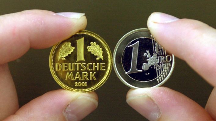 Eine Euro-Münze und eine goldene D-Mark werden zwischen Daumen und Zeigefinger gehalten. (Quelle: dpa/Frank Leonhardt)