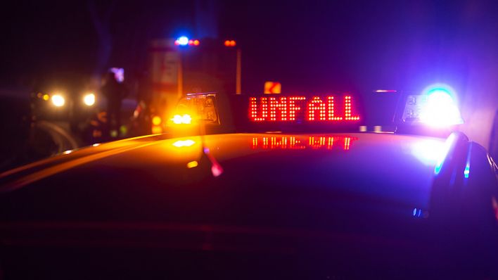 Ein Einsatzfahrzeug der Polizei in der Dunkelheit, mit Blaulicht und dem Schriftzug, Unfall, im Display. (Quelle: dpa/Fotostand / Gelhot)
