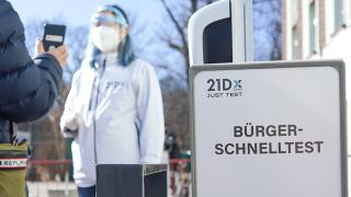 Eine Mitarbeiterin der Betreiber-Firma 21Dx GmbH und ein Bürger stehen vor einem Corona-Schnelltestzentrum in der Lehrter Straße (Bild: dpa/Jörg Canrstensen)