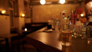Symbolbild: Ein halb geleertes Bier und andere benutzte Gläser stehen am 10.10.2020 kurz nach der Sperrstunde in einer Bar in Neukölln auf dem Tresen. (Quelle: dpa/Annette Riedl)