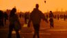 Menschen gehen im Licht der untergehenden Sonne über das Tempelhofer Feld. (Quelle: dpa/Stefan Jaitner)